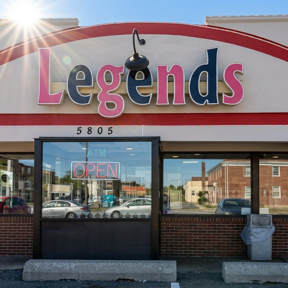 Street-facing exterior of Legends restaurant with a colorful sign, open neon doorway, large windows, and sunny parking lot.